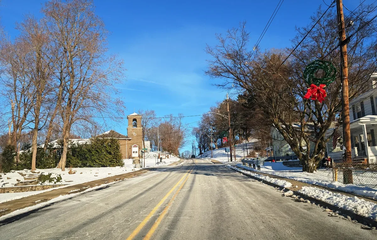 Main Street in Franklin, New Jersey, with older homes and a stone church tower in winter